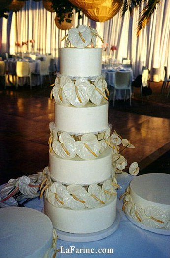 A tiered wedding cake decorated with anthurium flowers